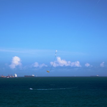 Fotografia. Linhas do horizonte com nuvens e pipa.
