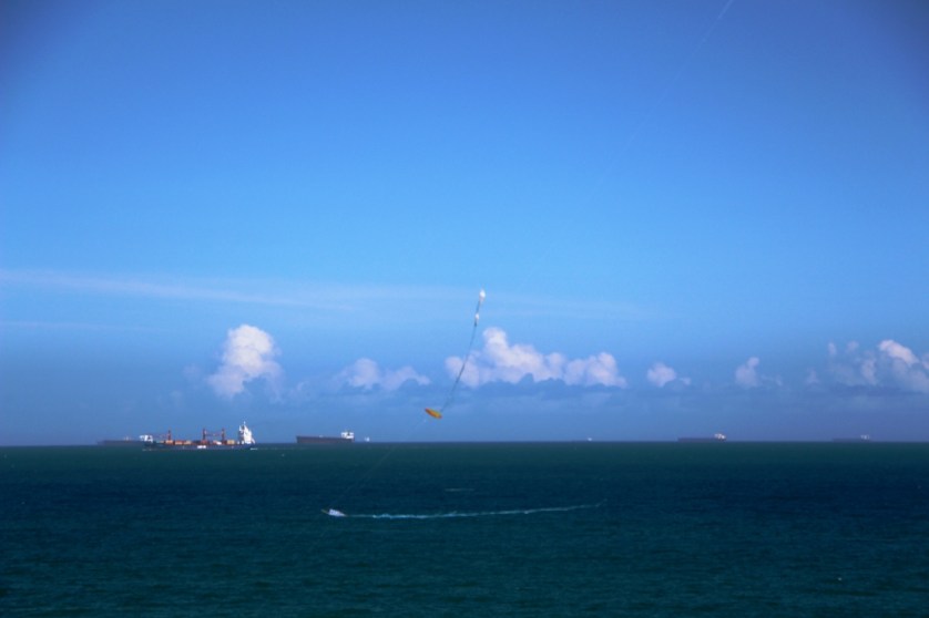 Fotografia. Linhas do horizonte com nuvens e pipa.