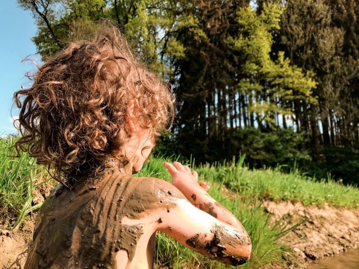 Fotografia de menino de costas coberto de lama